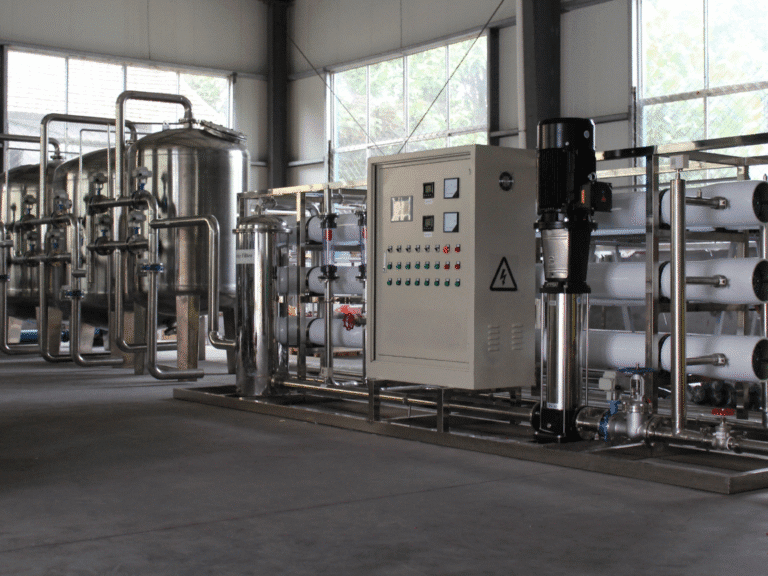 A modern industrial water treatment facility featuring stainless steel tanks, filters, control cabinets, and pump systems.